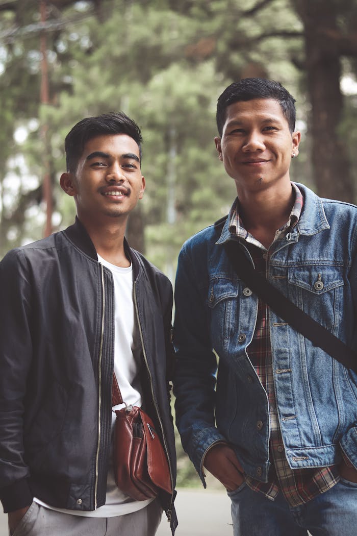 Two young men in jackets smiling and standing outdoors. Perfect for lifestyle and fashion themes.
