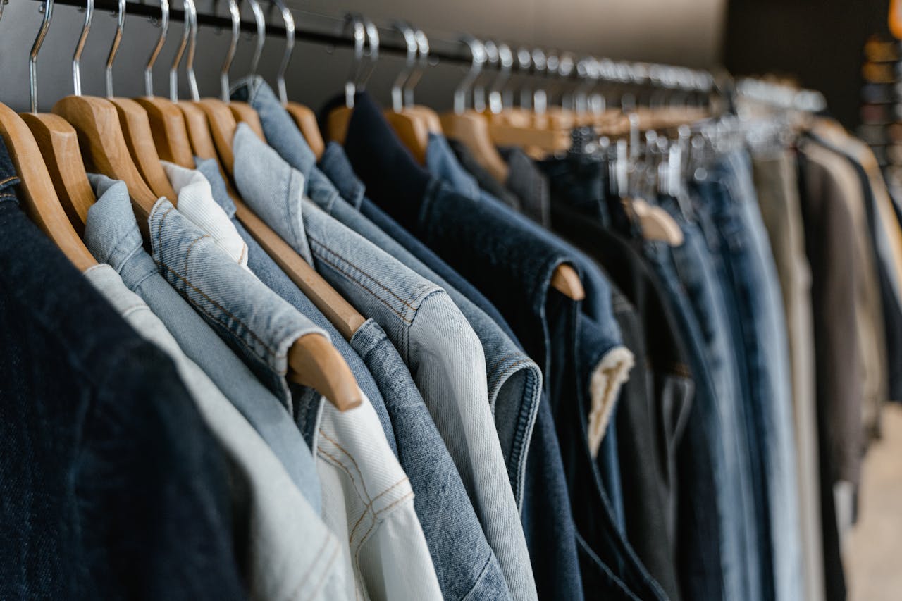 A close-up view of various denim jackets hanging on a clothes rack indoors.